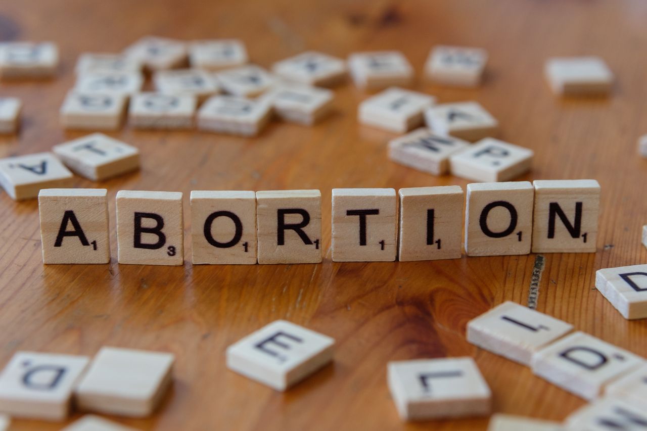 Services Scrabble tiles spelling 'abortion', highlighting the debate on reproductive rights.