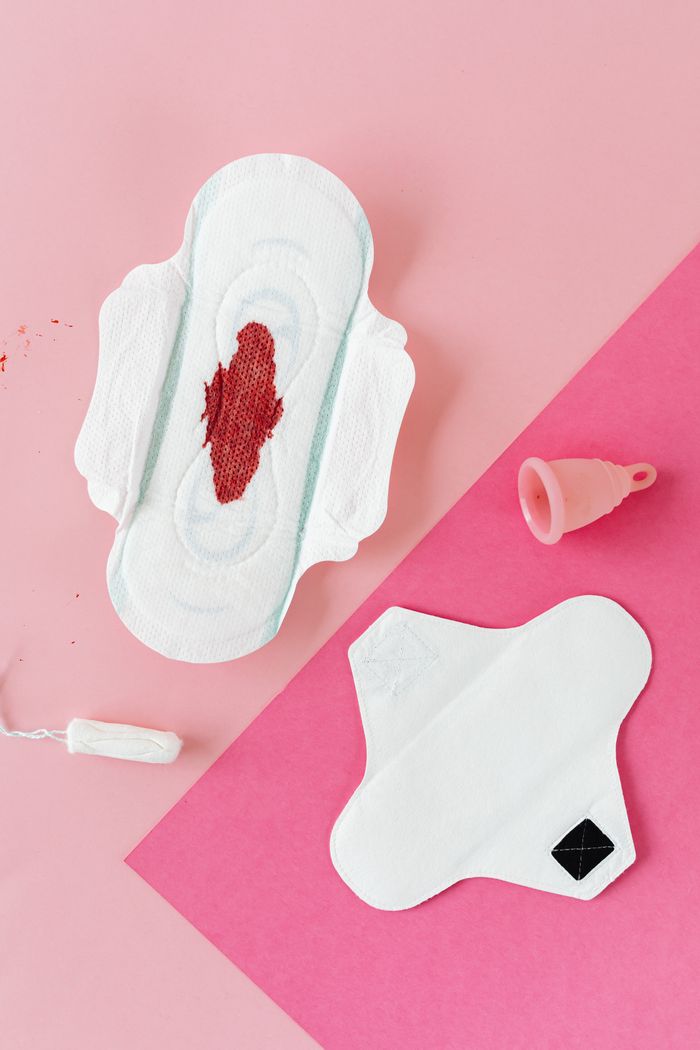Services Various menstrual hygiene products on a pink background, illustrating period care.